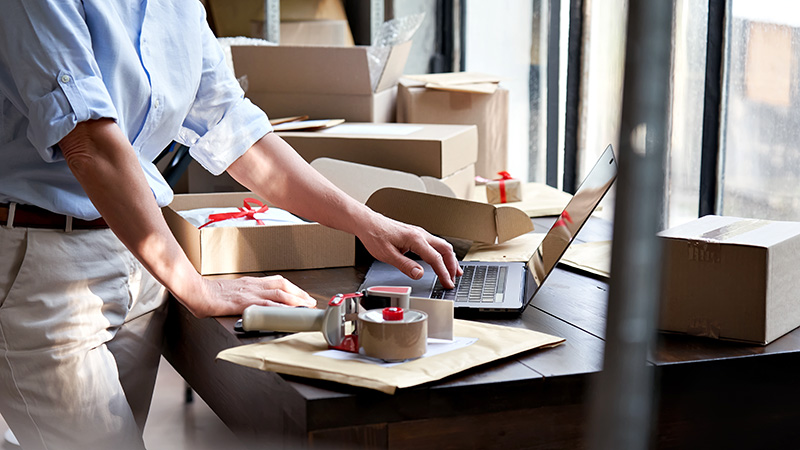 A small business owner using a laptop to manage shipping and logistics, supported by JTC’s reliable high-speed fiber internet.